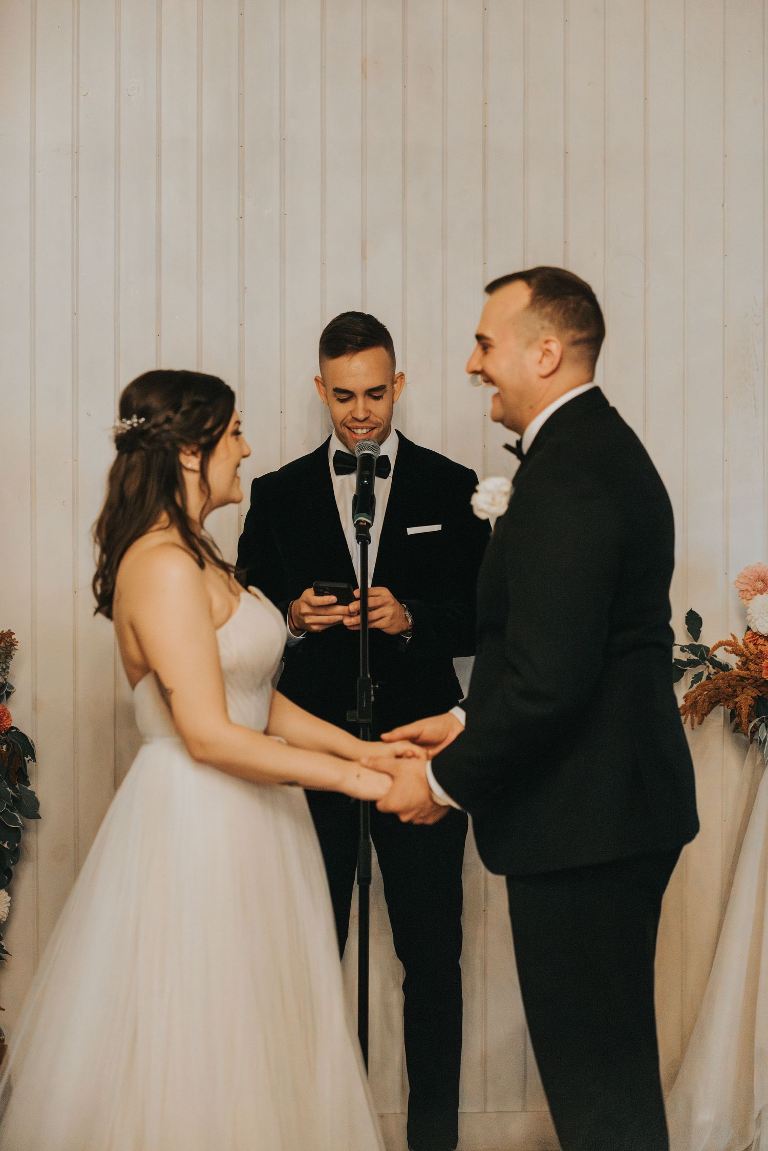 A wedding ceremony taking place inside with attendees exchanging vows in front of an officiant during the service.