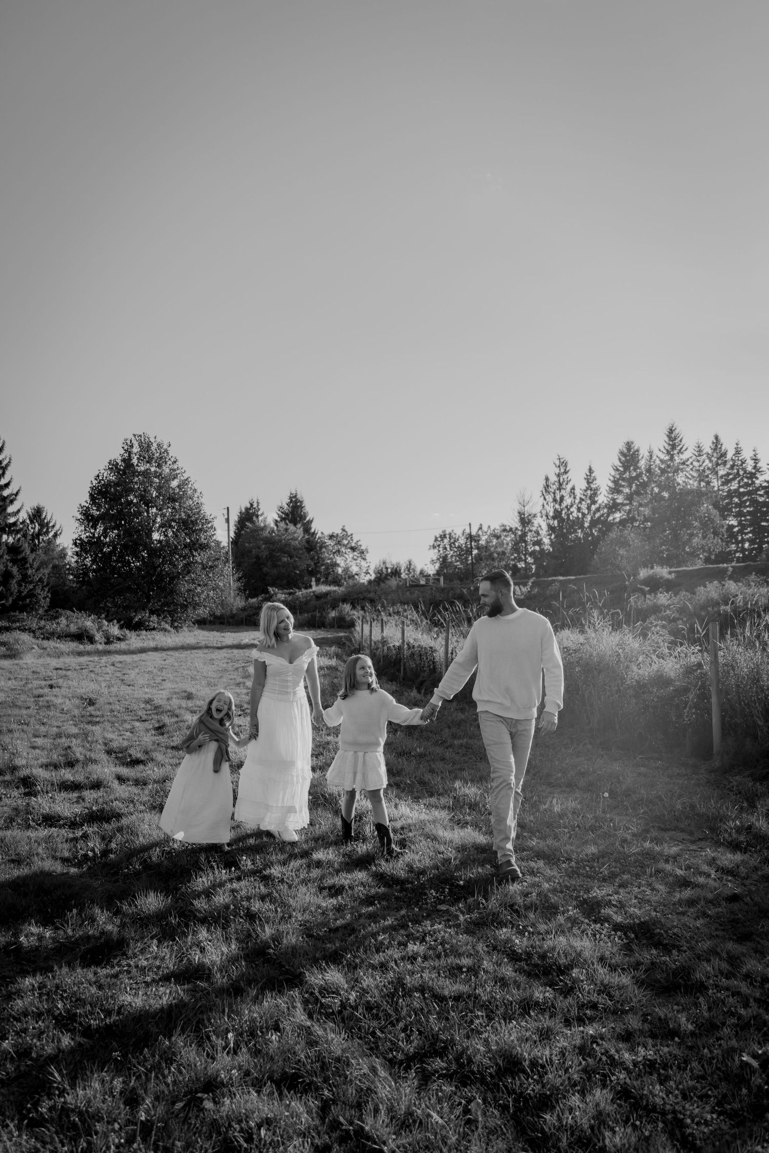 A group of people walk together up a grassy hillside in black and white, creating a serene silhouette against nature.