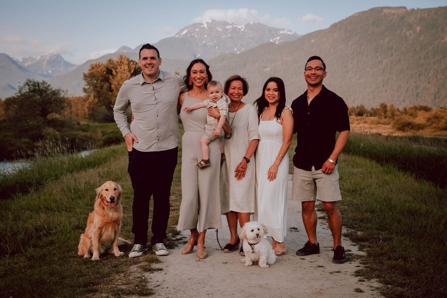 Family portrait with two couples, children and dogs standing together with mountains in background.