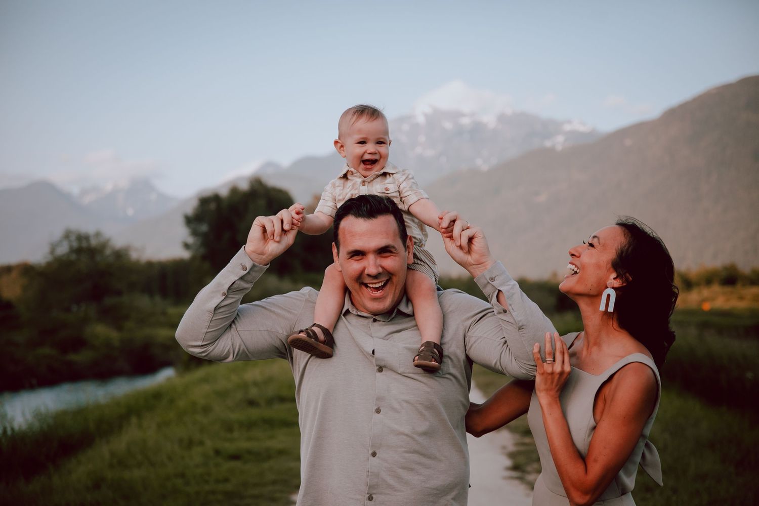 Family sharing a candid laughing moment outdoors with mountains in the background.