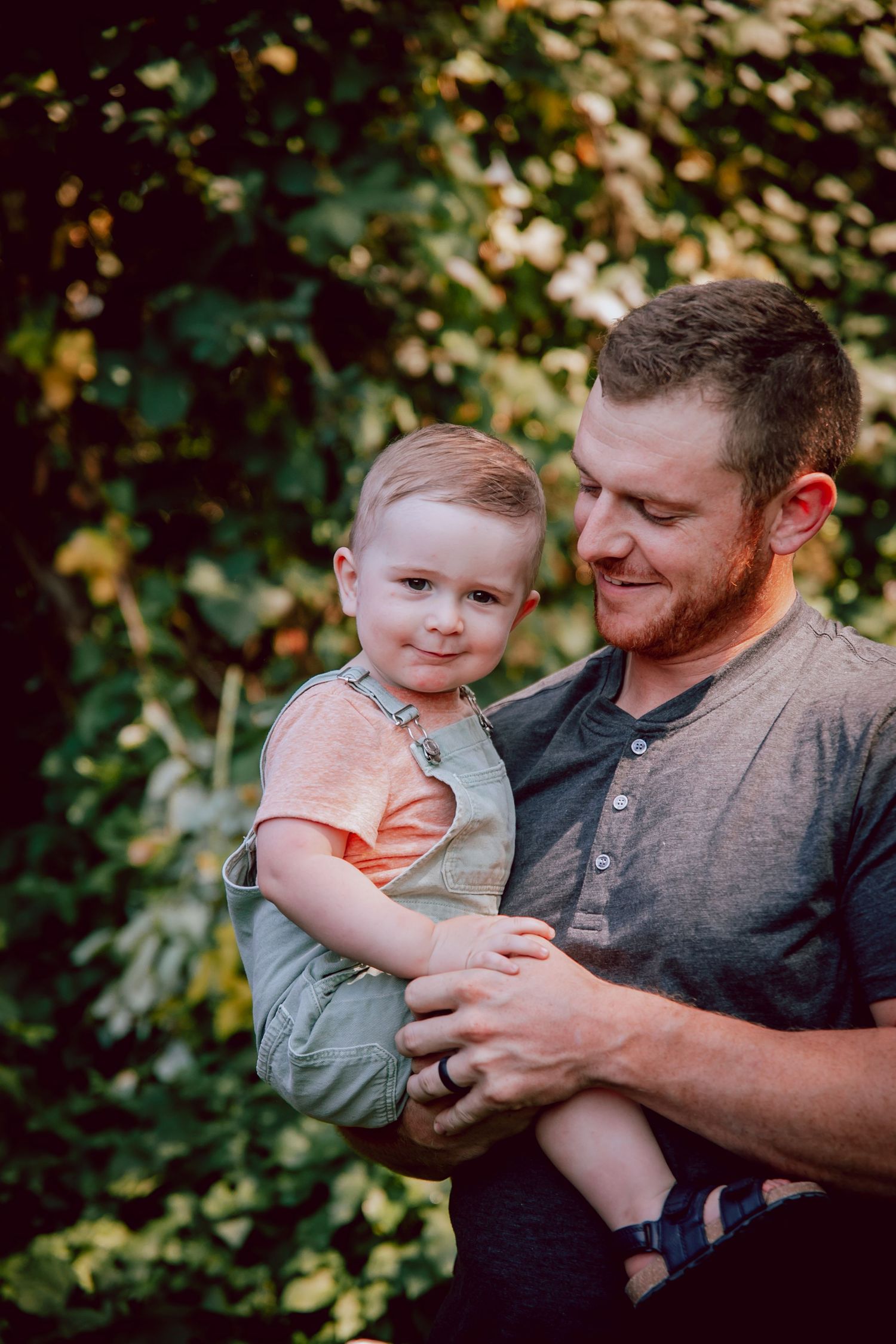 A tender moment between parent and child outdoors with autumn foliage in the background.