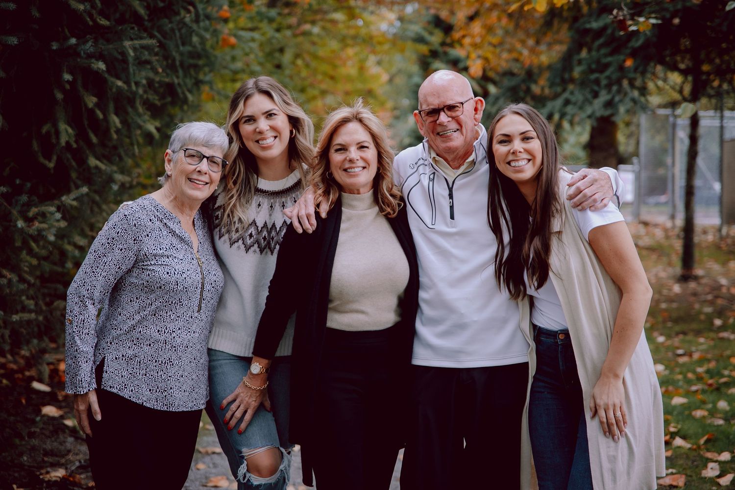 A family group poses together for a portrait in a fall setting with colorful foliage.