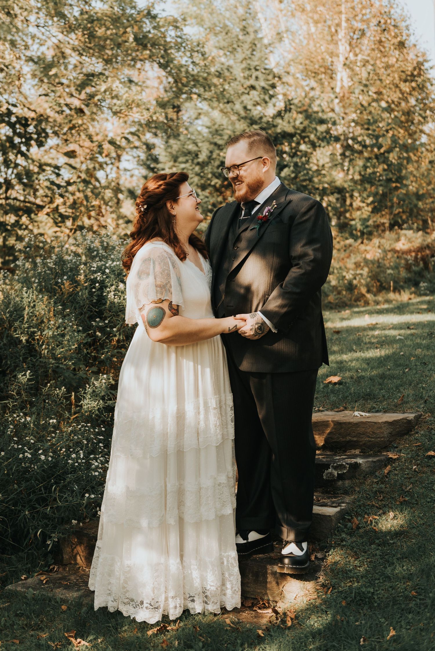 A couple shares an intimate moment in a whimsical outdoor setting, dressed in wedding attire against autumn foliage.