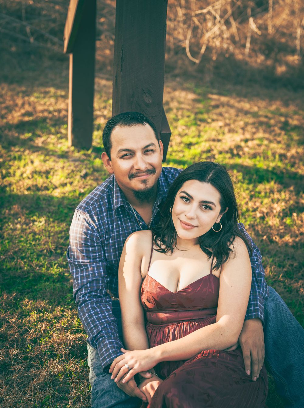 A romantic outdoor couple portrait shows a young couple sitting together in a casual setting with natural lighting effects.