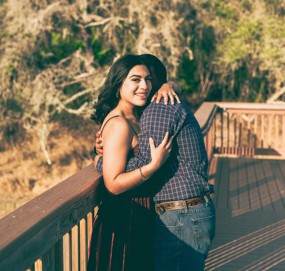 Two people having an intimate moment on a wooden deck overlook during golden hour.