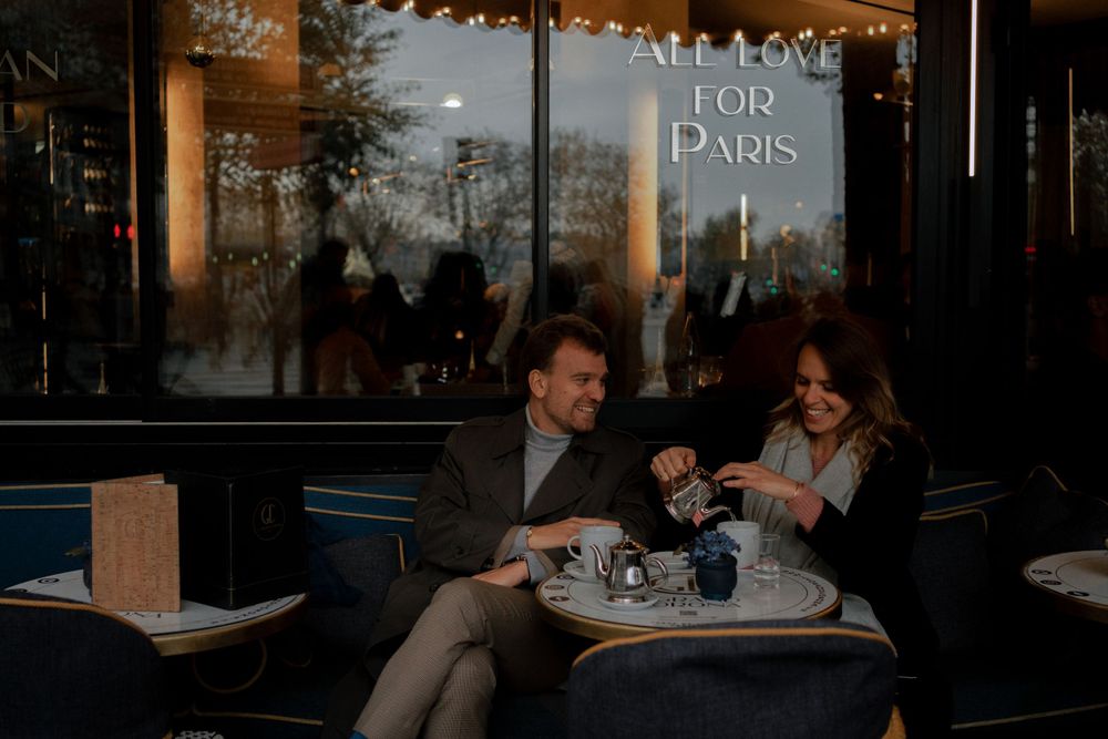 Two people enjoying coffee and conversation at a Parisian cafe during sunset.