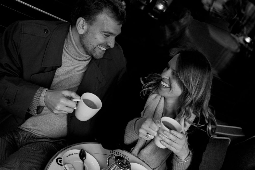A couple enjoying coffee and conversation at a cafe table in black and white photography.