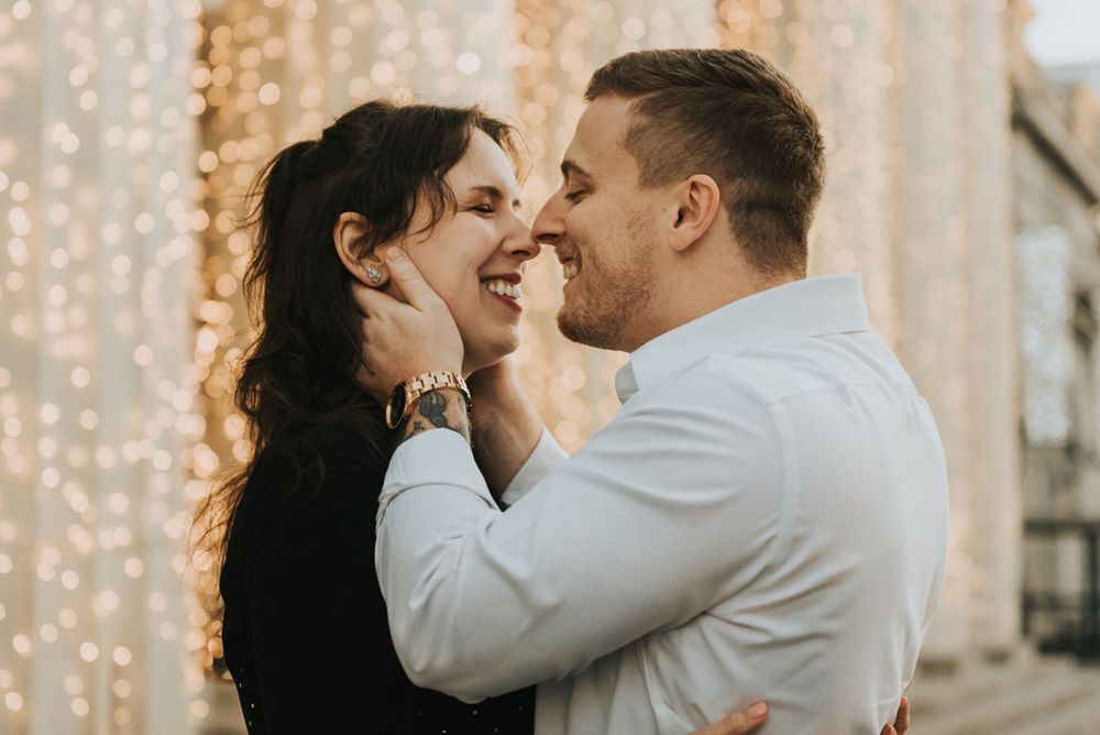 Romantic couple sharing an intimate moment against a backdrop of twinkling string lights.