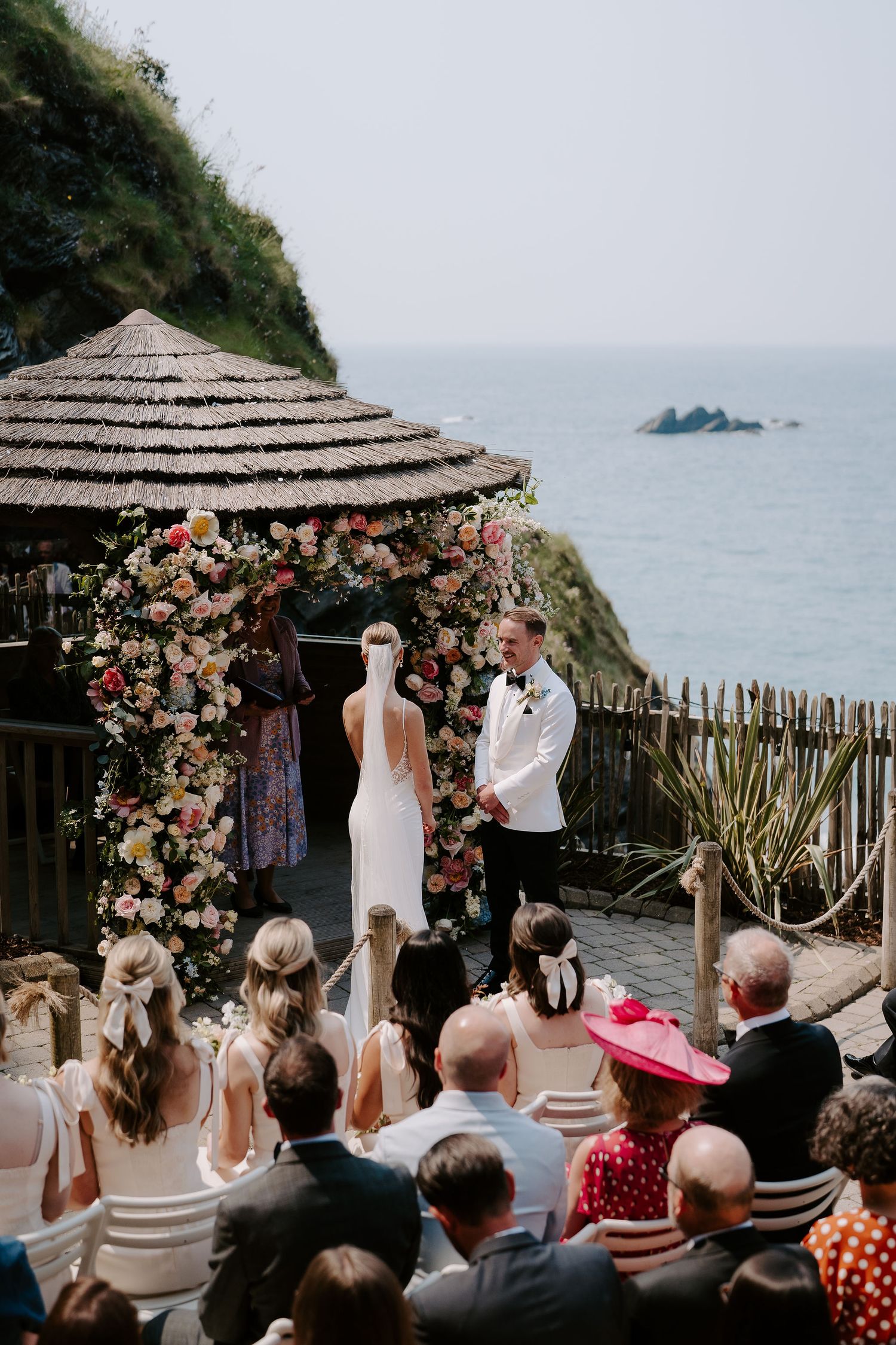 Bride and Groom in front of floral arch next to the sea at Tunnels Beach Wedding Venue in North Devon