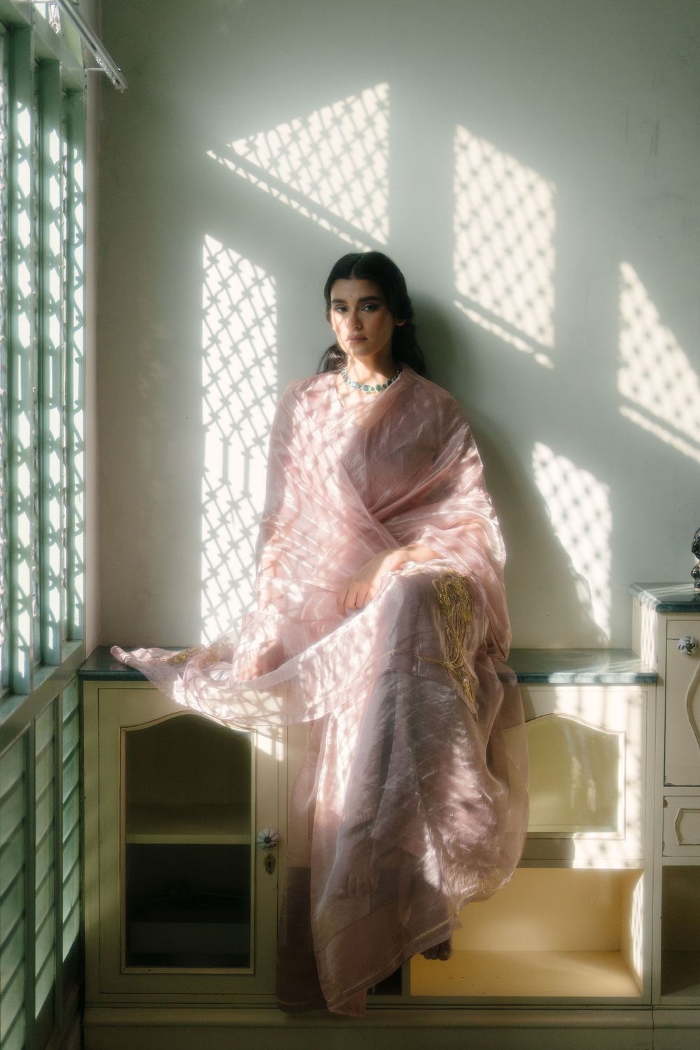 Fashion portrait with latticed window shadows on pink traditional dress.