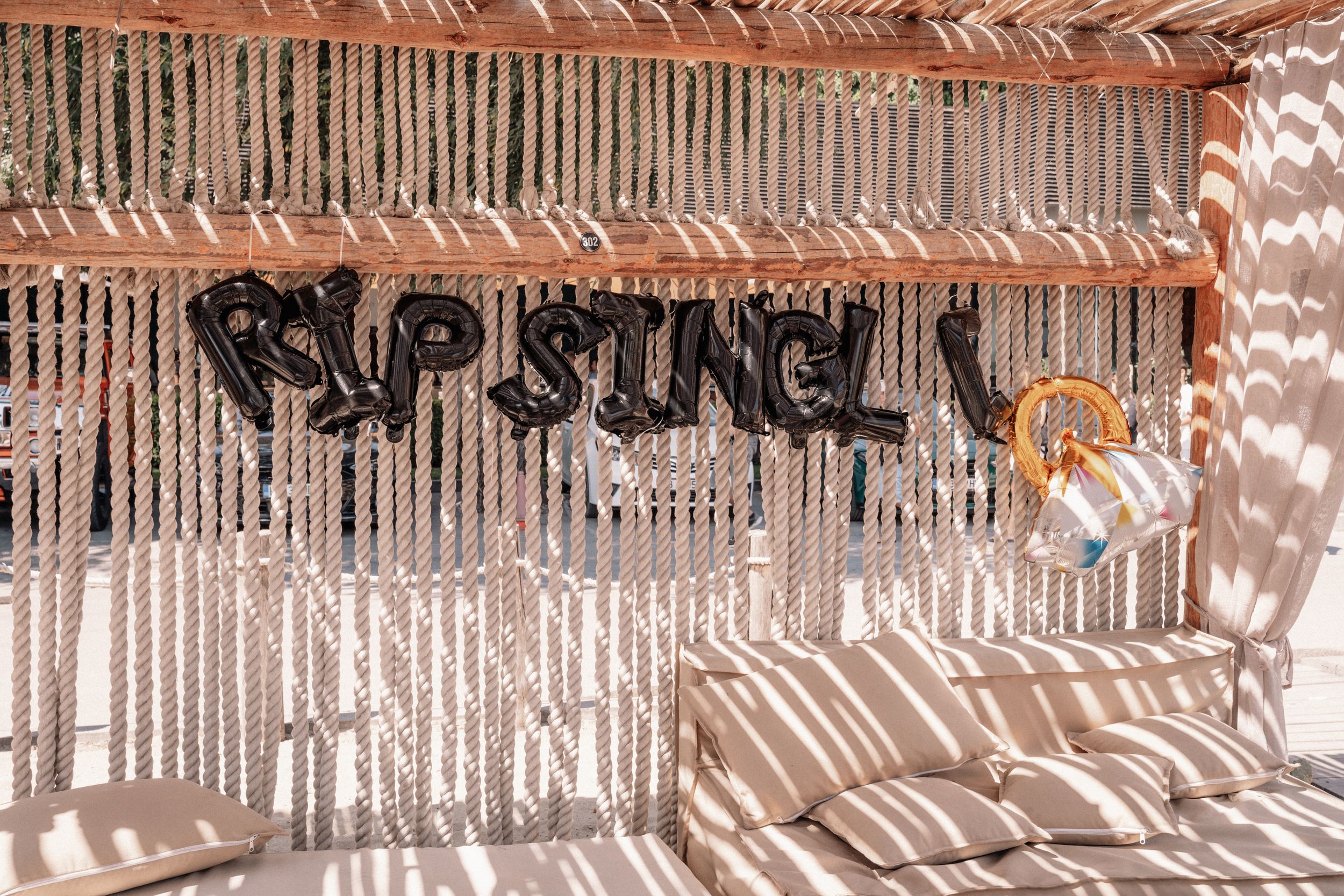 Rustic wooden wall with 'Rip Stingl' text and decorative string lights creating shadow patterns.