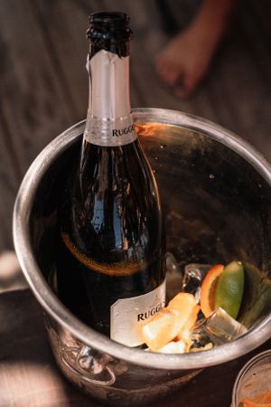 Bottle of Ruinart champagne chilling in ice bucket with citrus garnishes.