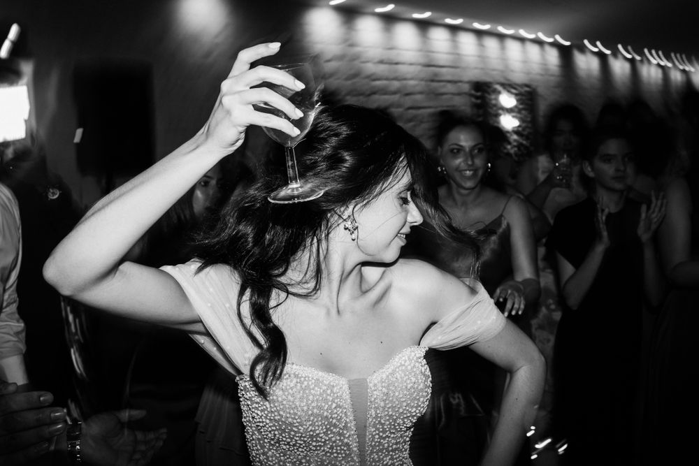 Bride in strapless dress dancing at wedding reception under dim lights.
