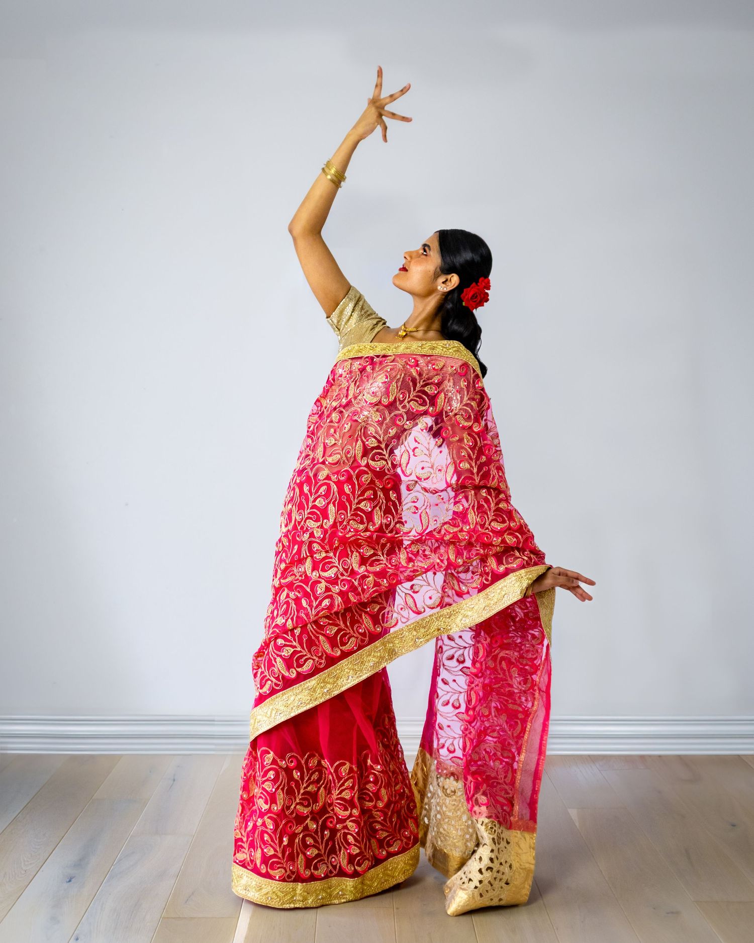Dancer in red and gold traditional Indian sari strikes graceful pose with raised arm. Indian photographer near me