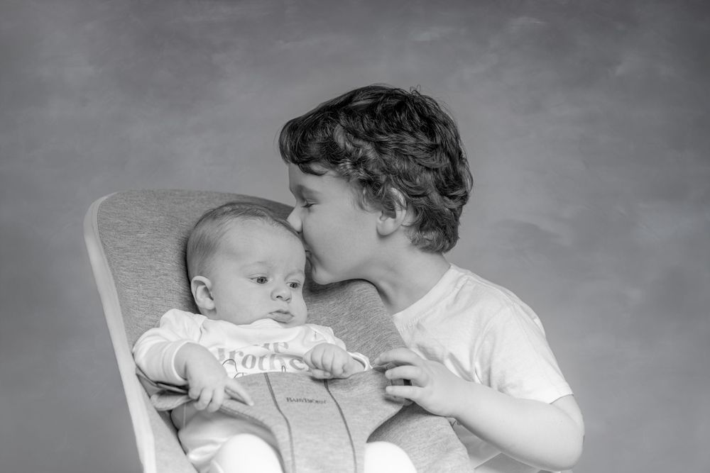 A heartwarming black and white photo series showing tender moments between a parent and baby in various poses.