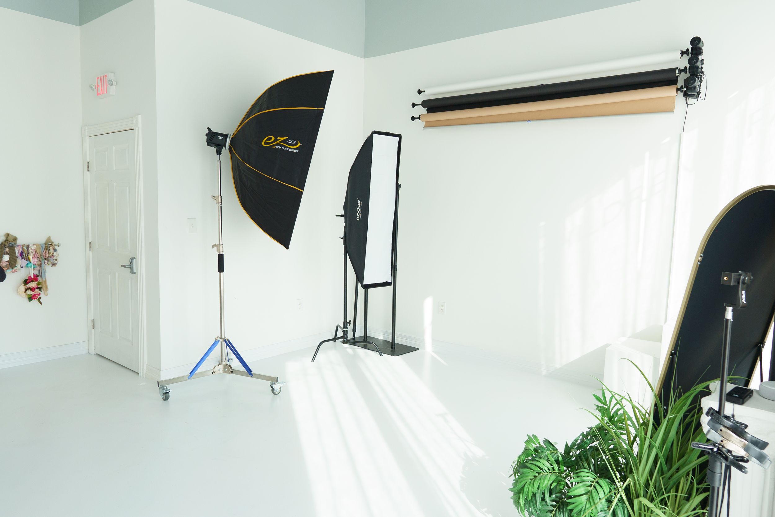 Photography studio interior with backdrop stands, softboxes, and white seamless paper setup.