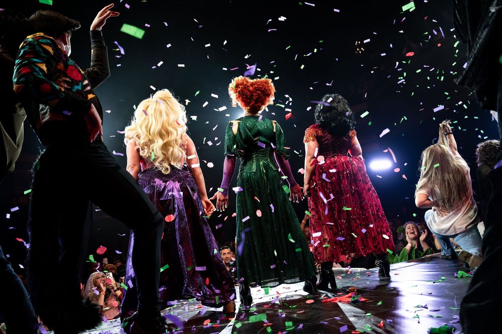 Crowd at concert venue with colorful confetti falling during live performance under stage lights.