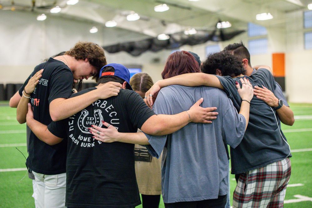 Students forming a group huddle during indoor team building exercise.