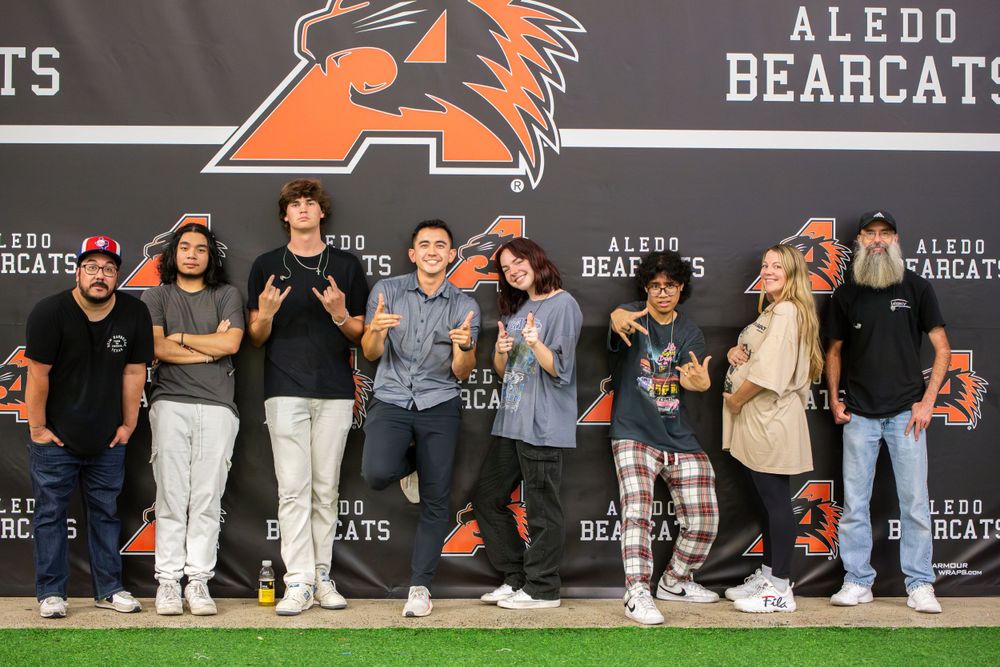 A group of people gathered in front of an Aledo Bears banner during what appears to be a school or sports event.
