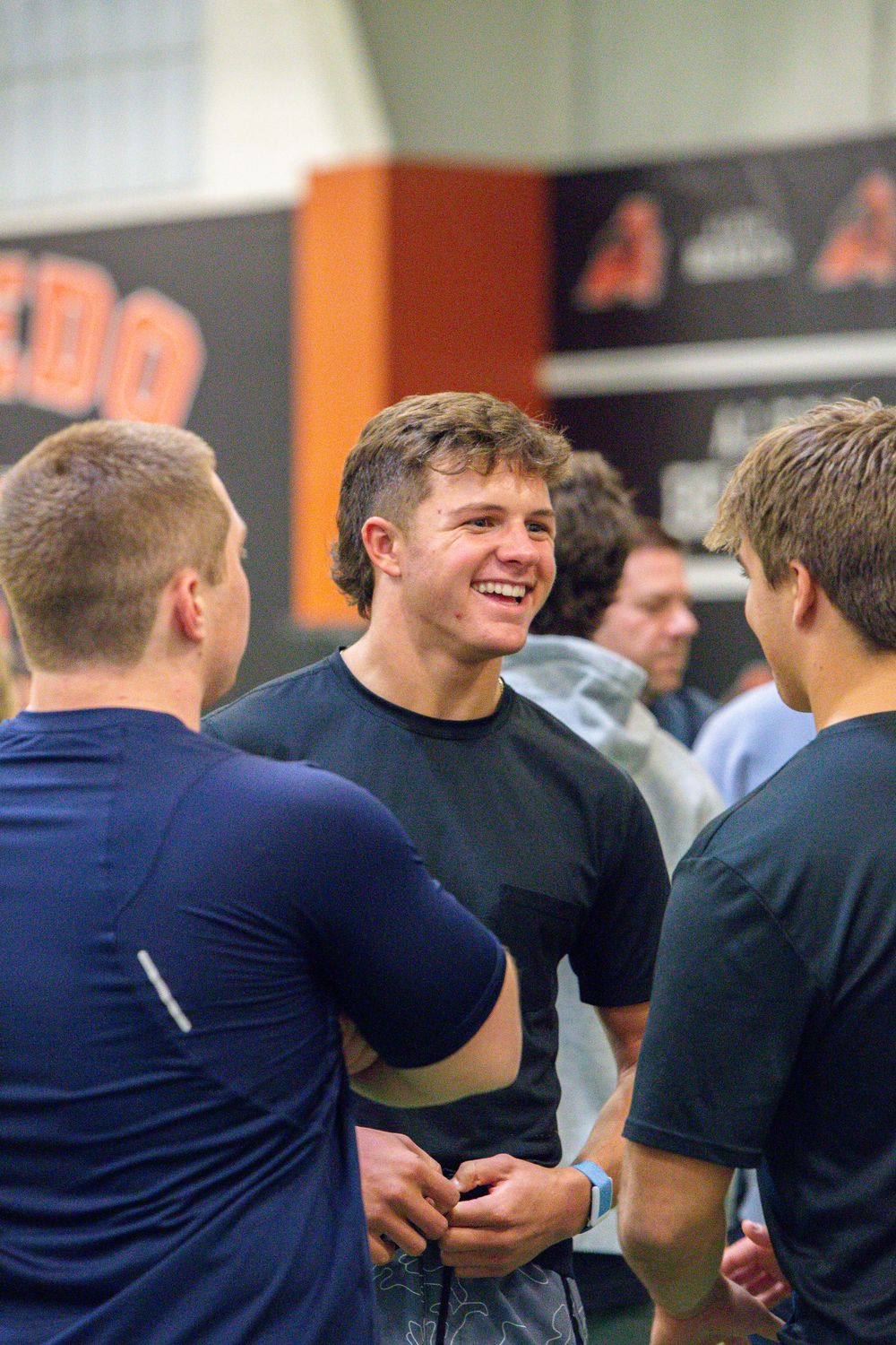 Group of individuals sharing laughs and conversations in an indoor athletic facility.