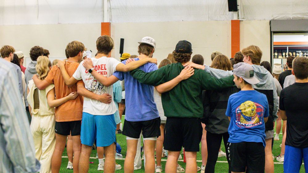 A large group forms a connected line with arms around shoulders in solidarity.