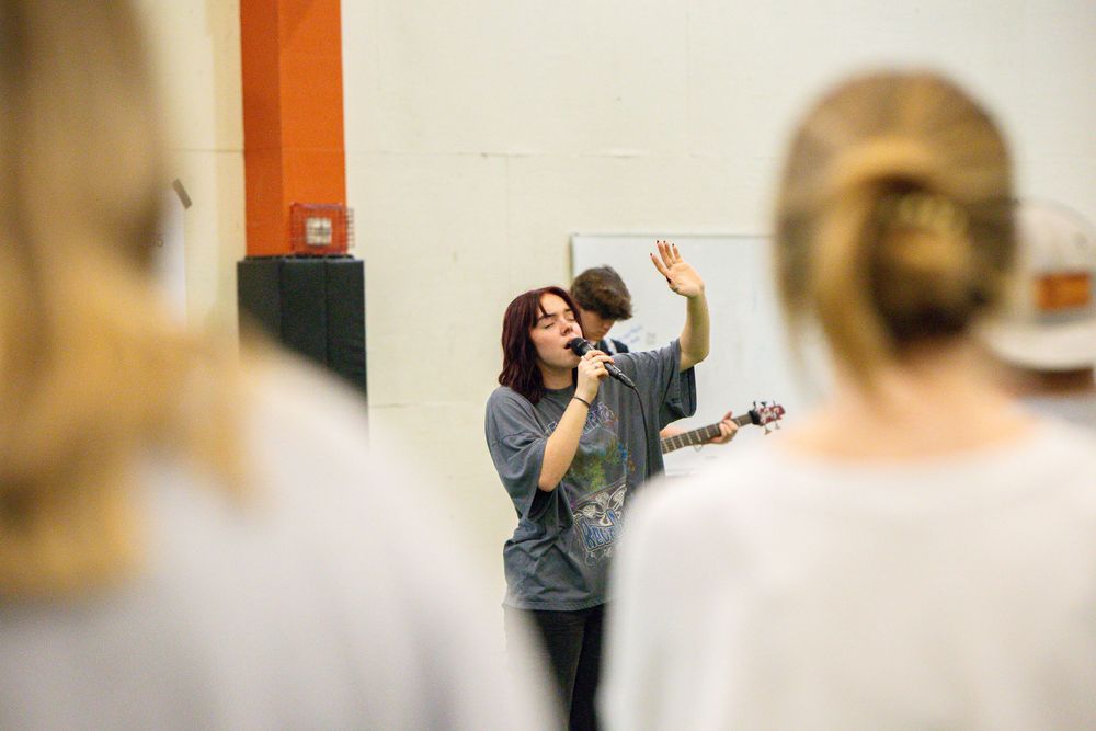 People standing together in a blurred indoor setting with orange accents visible.