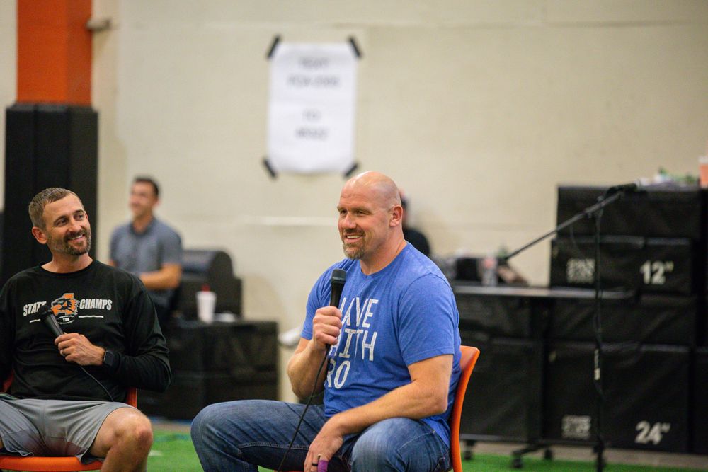 People gathered in a gym or training facility having animated conversations.