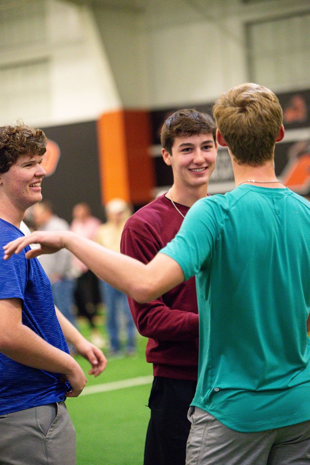 Students participating in team building activities on indoor green turf field.