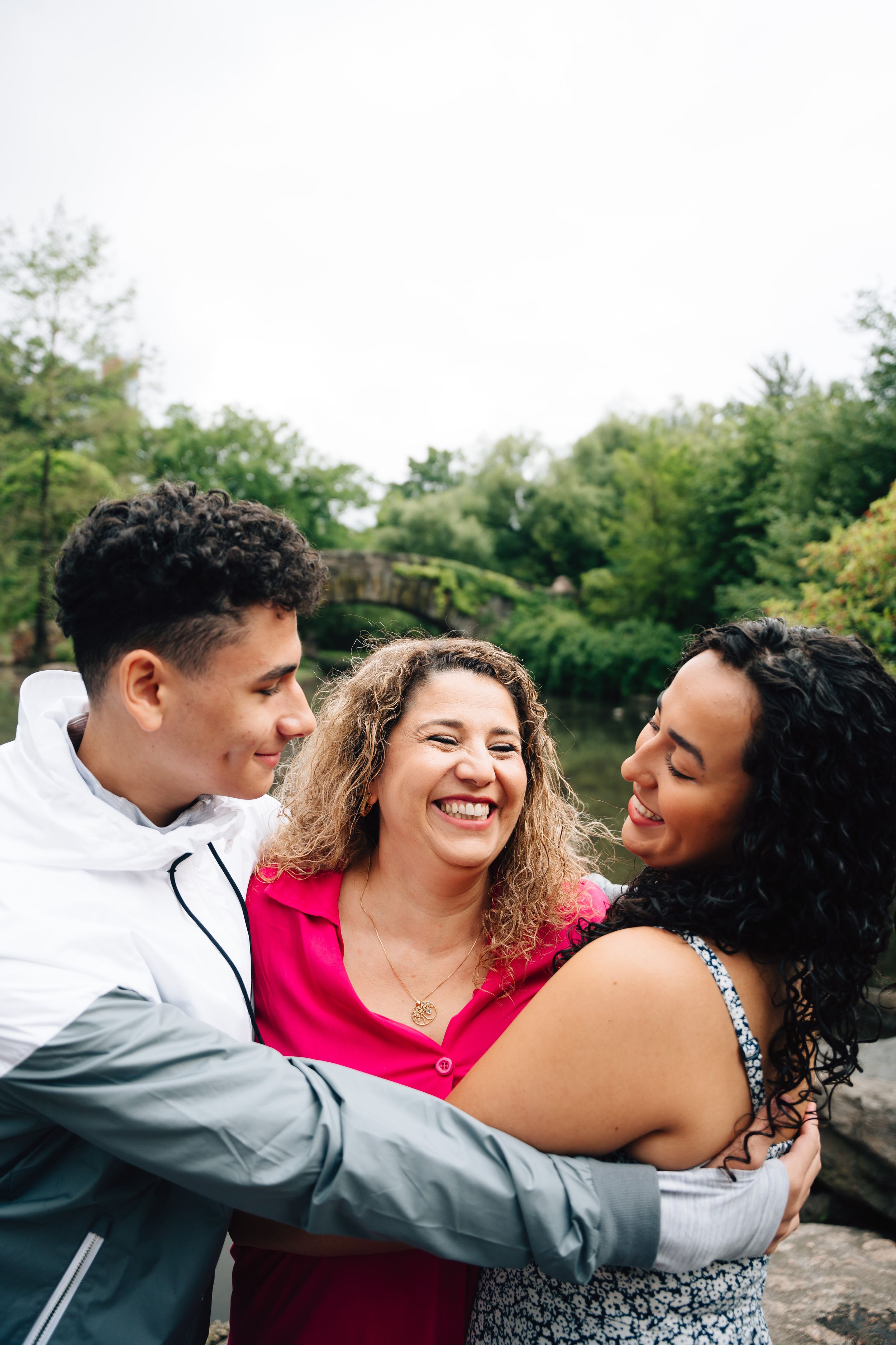 Three friends share a joyful moment together outdoors with natural greenery in the background.