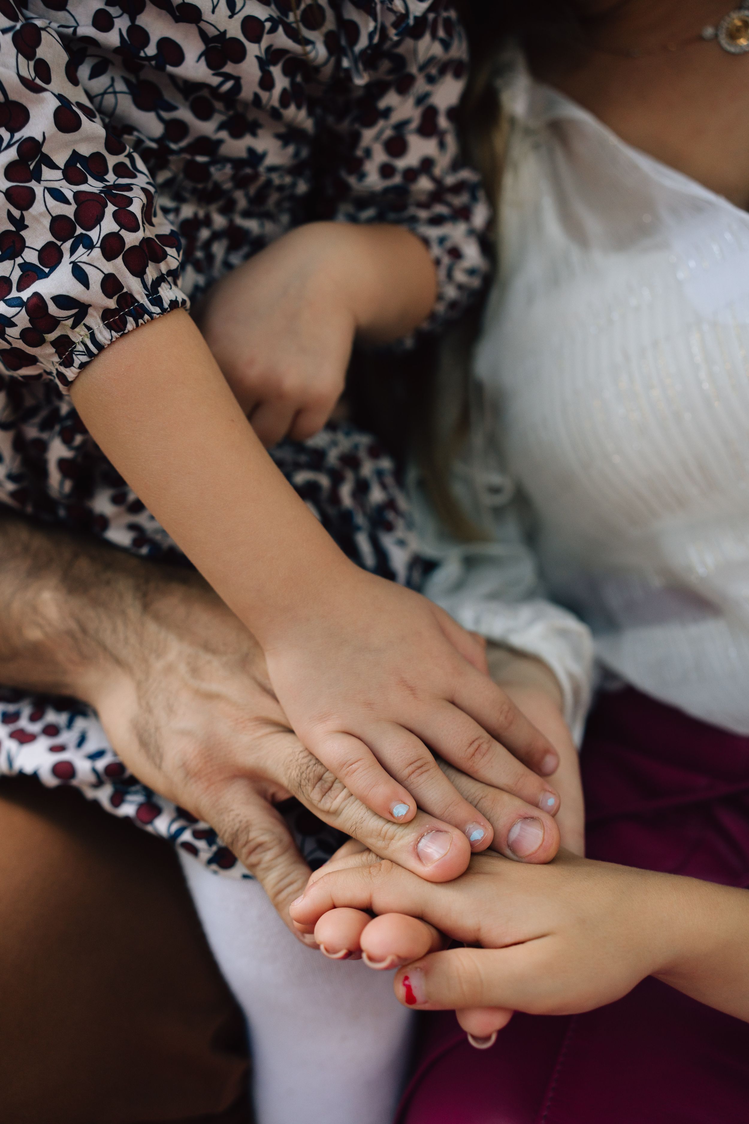 Hands reaching out to comfort and hold each other in an intimate display of care and support against a floral pattern background.
