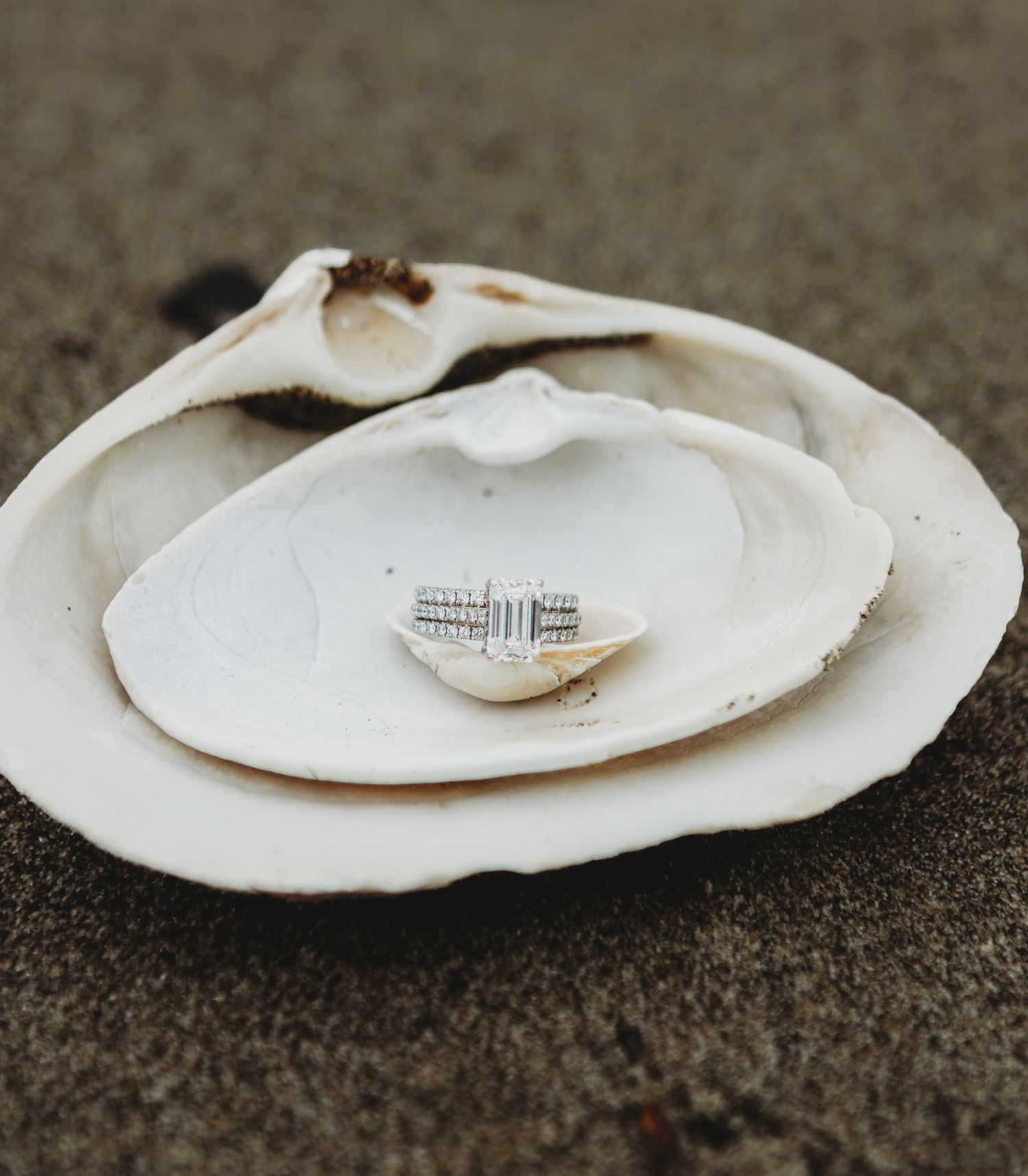 Close-up of a woman showing off her diamond engagement ring while holding hands with her partner outdoors.
