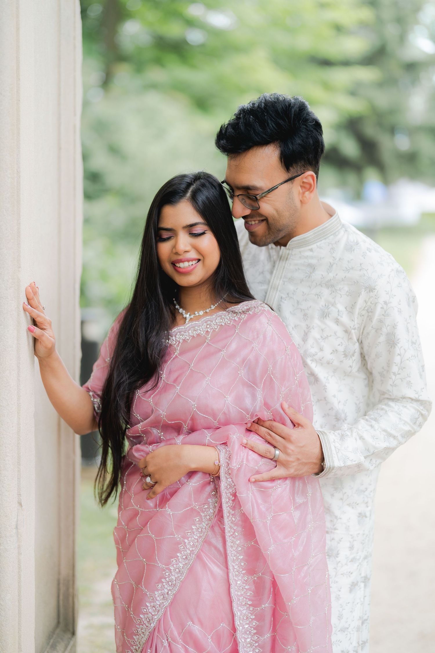 Indian couple walking together, bride in red saree and groom in black suit.