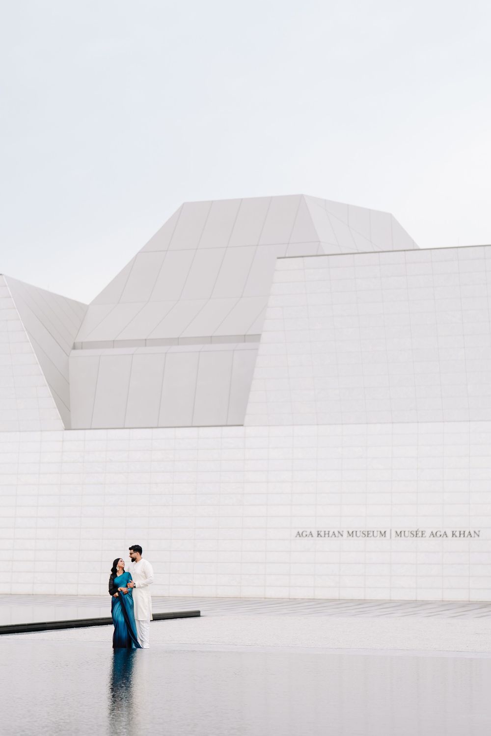 Couple embracing in front of the white geometric Aga Khan Museum in Toronto, Canada.