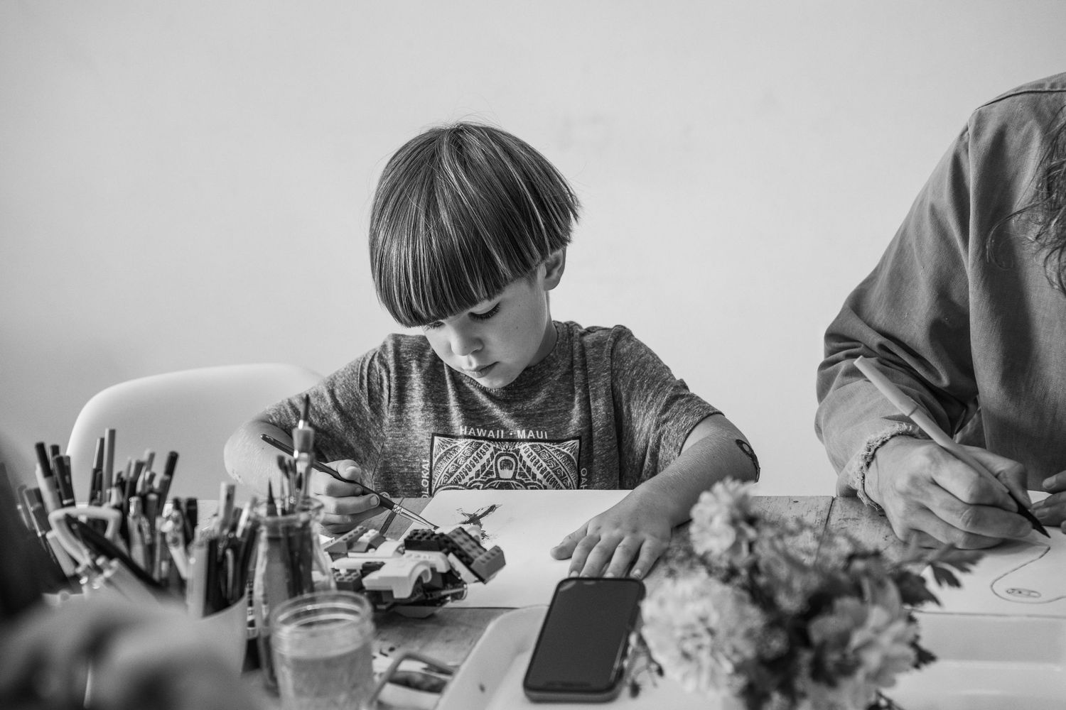 Mother and child sitting on a white bed reading a book together in a cozy bedroom with soft lighting.