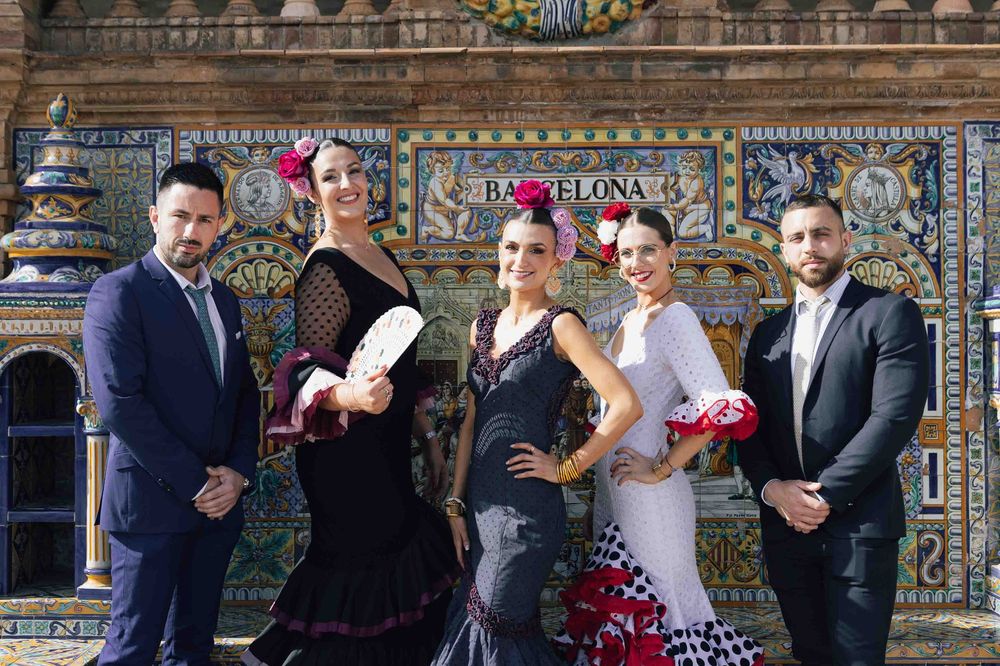 Flamenco dancers and men in suits pose in traditional Spanish attire at Plaza de España, Barcelona.