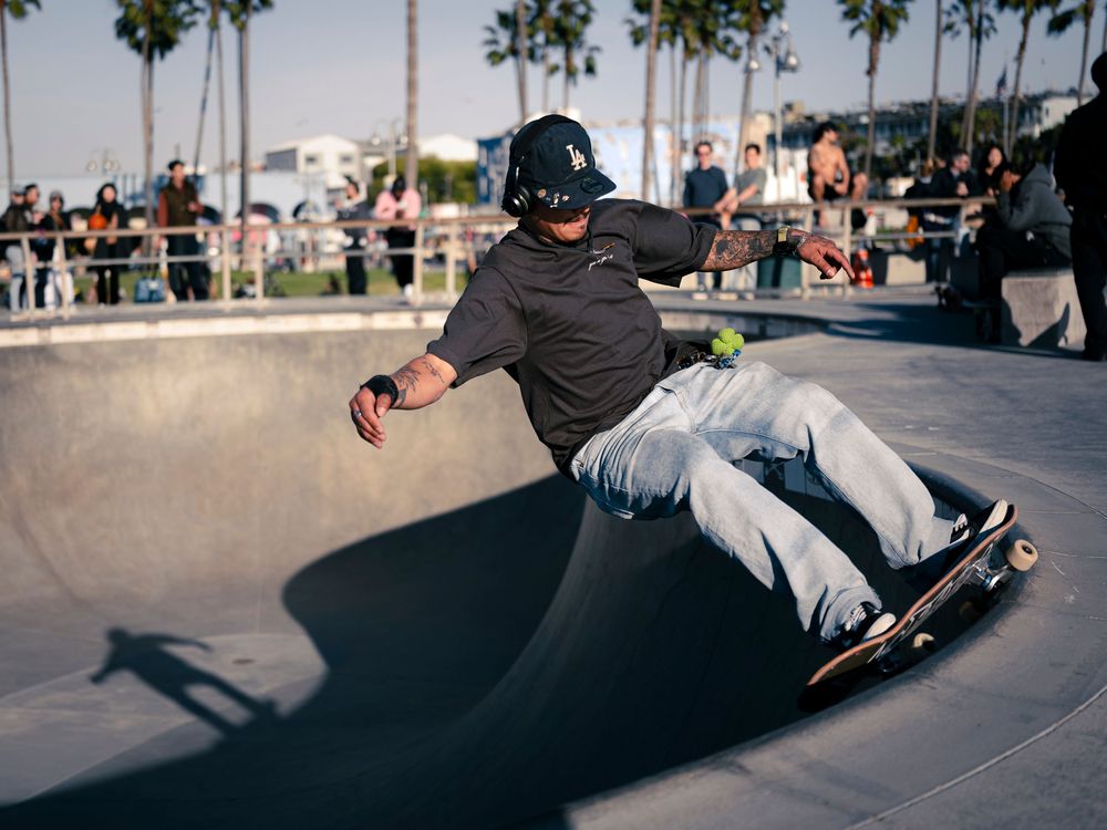 Skateboarder performing a trick on the curved edge of a skate bowl at Venice Beach skate park.