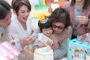 Family celebrating a child's birthday with a colorful cake, smiling and gathered together at a festive party.