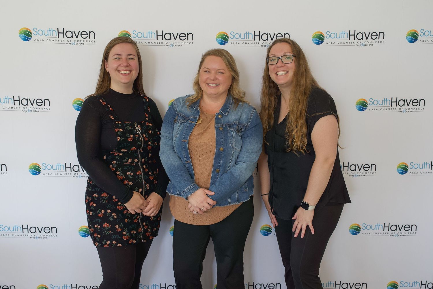 Three smiling women posing together in front of a SouthHaven branded step-and-repeat backdrop.