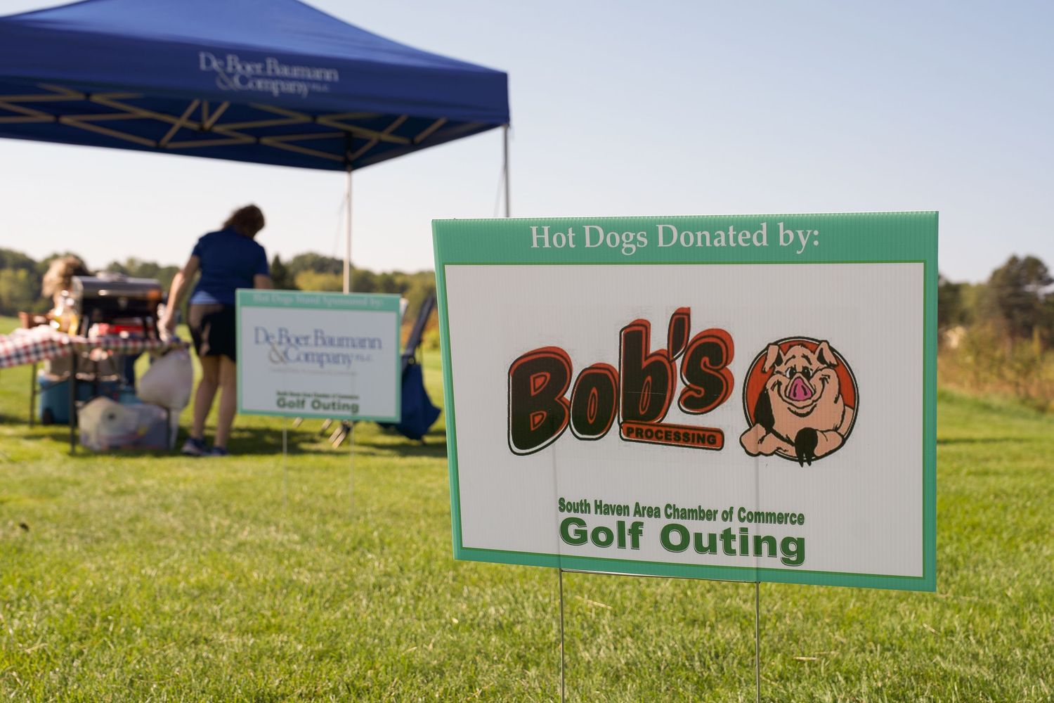 Bob's hot dogs donation sign at South Haven Area Chamber of Commerce Golf Outing on green grass field.