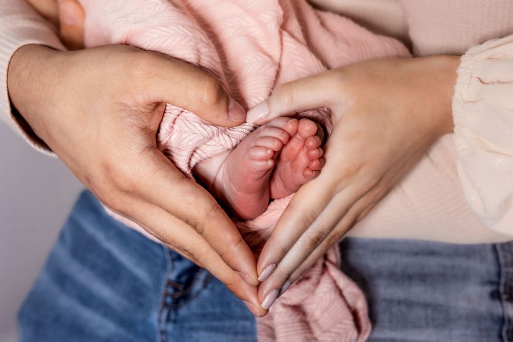 Close-up of newborn feet held by parents' hands in Fresno, CA.