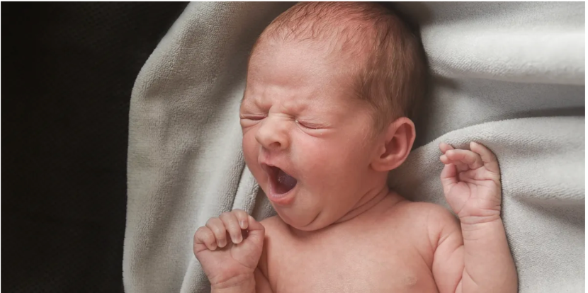 Series of black and white photos showing a yawning newborn baby on white bedding.