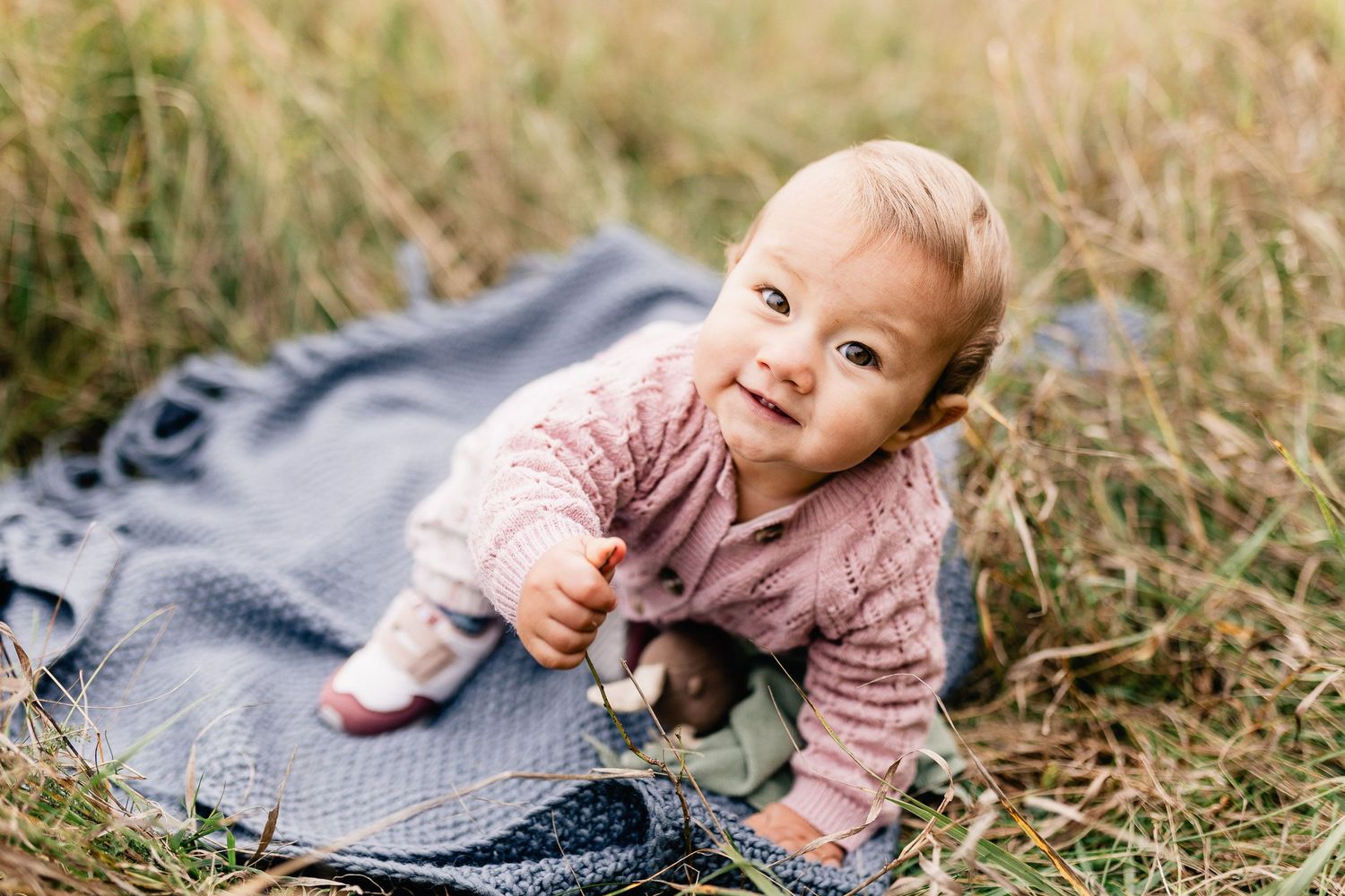 Eine vierköpfige Familie sitzt während eines Fotoshootings im Freien an einem freundlichen Tag auf einer Wiese zusammen.
