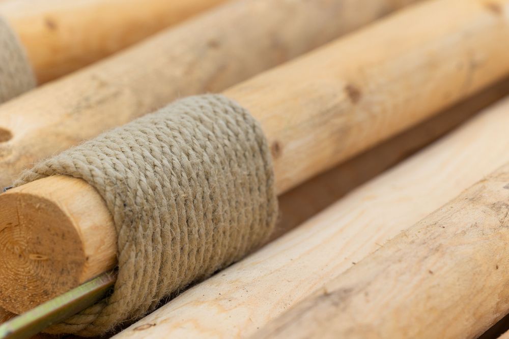 Close-up of wooden logs bound together with natural twine rope, showcasing rustic craftsmanship and organic textures.