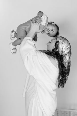 Black and white photo of a mother lifting her baby up for a kiss taken by pierce county photographer in roy washington studio