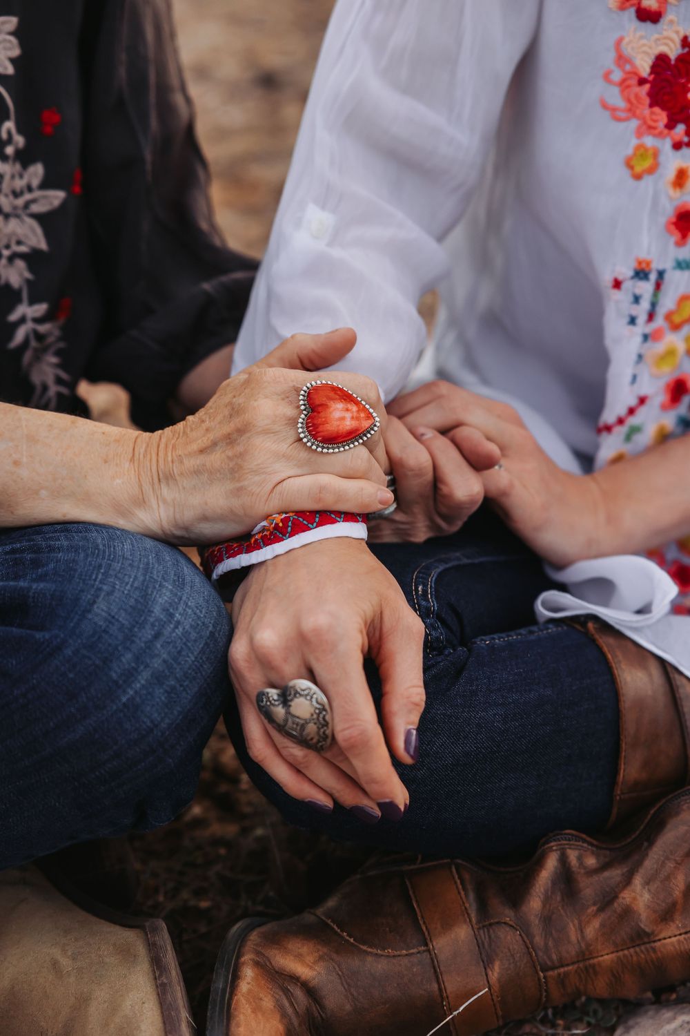 Close-up of hands wearing red heart and silver concho rings with a beaded bracelet.