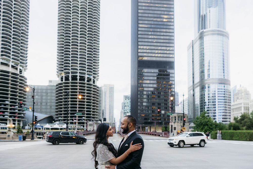 Couple embracing romantically in front of Chicago skyline with Marina City towers and Trump Tower in background during engagement session