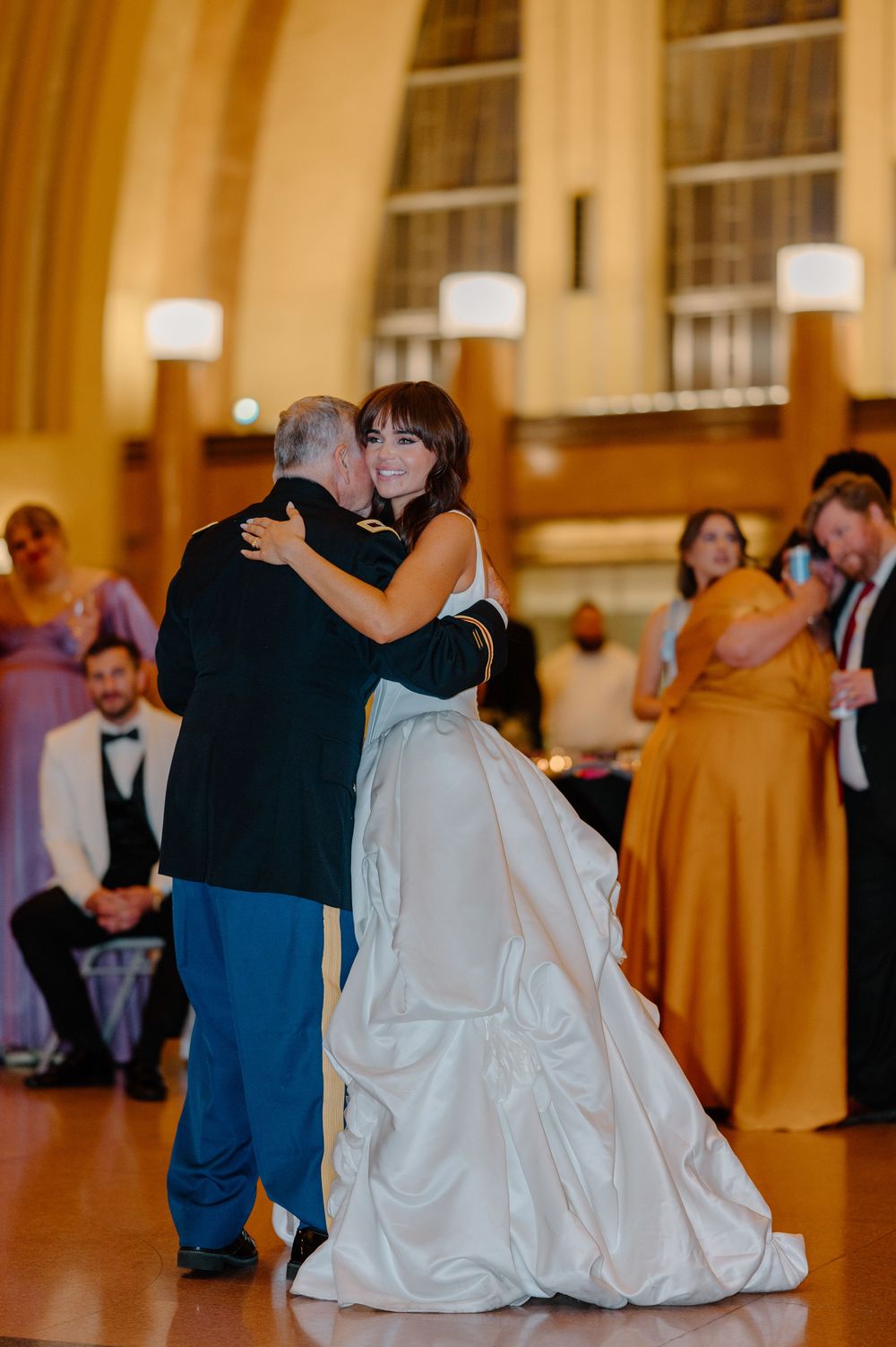 Bride in white ballgown shares emotional father-daughter dance at elegant wedding reception.