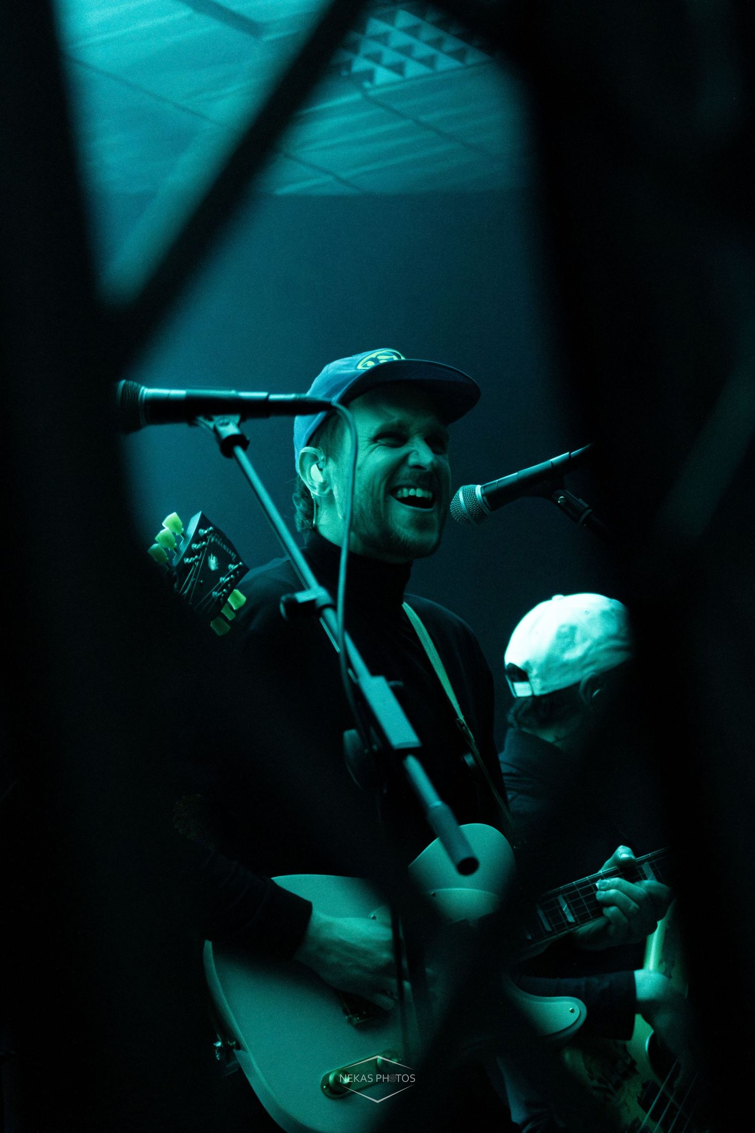 Guitarist performing live on stage under purple lights, playing a white Telecaster electric guitar while smiling.