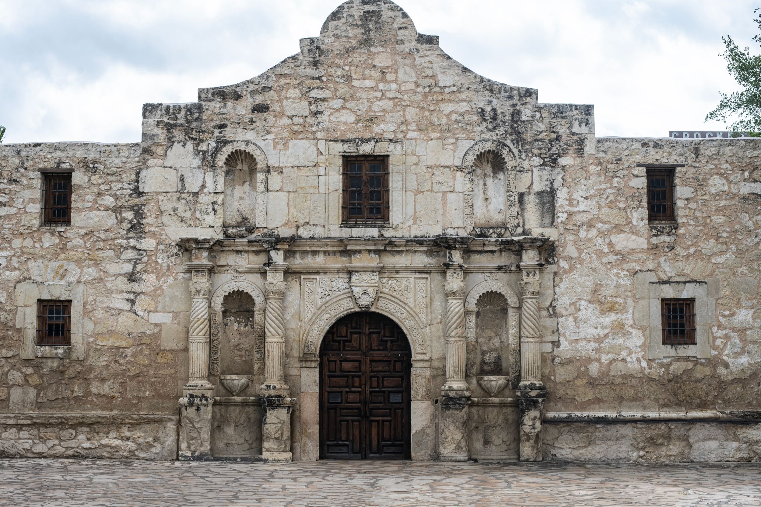Historic Alamo mission facade in San Antonio, Texas, featuring ornate stone architecture and wooden doors.