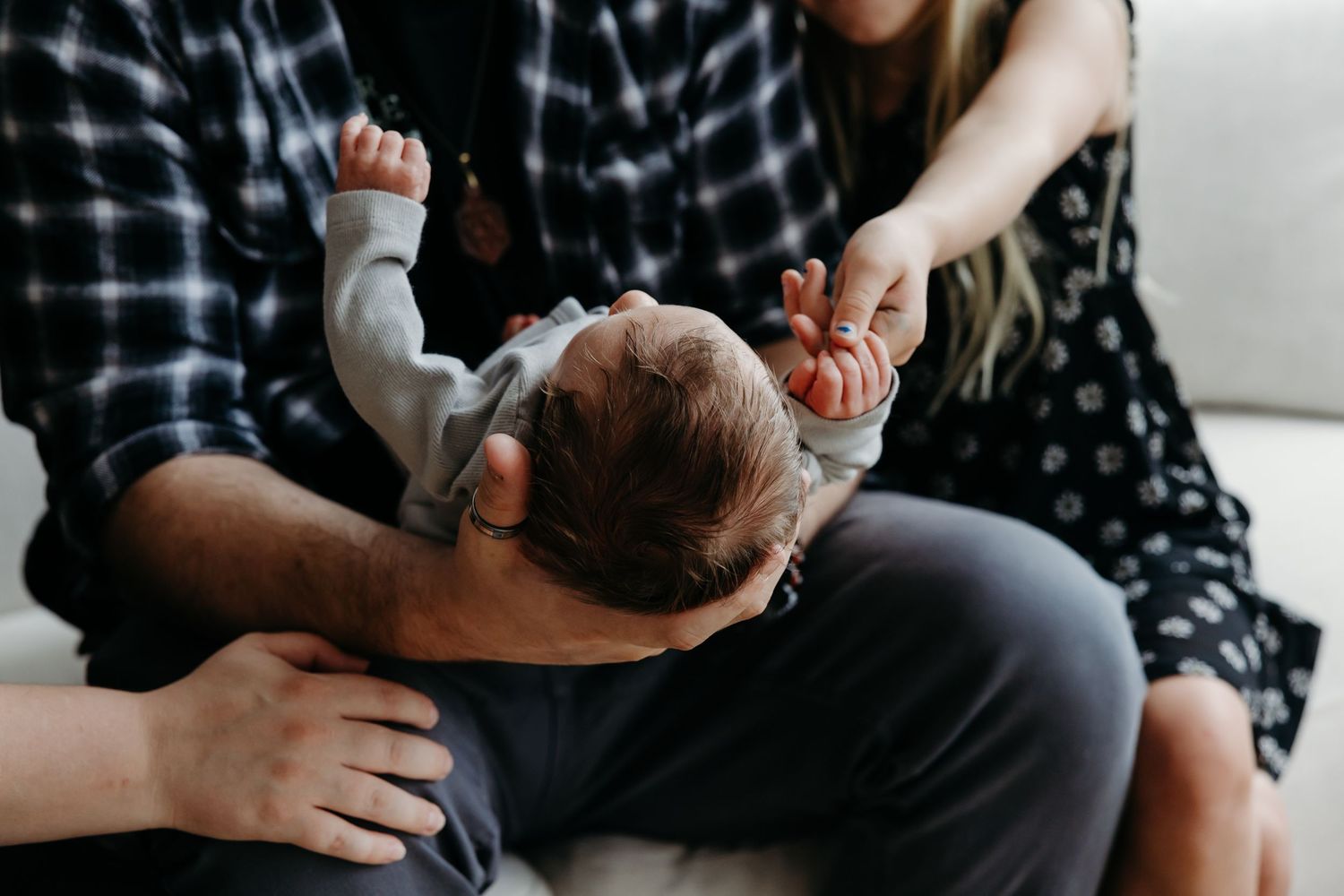 Parents lovingly holding their newborn baby together on a couch, sharing a tender family moment.
